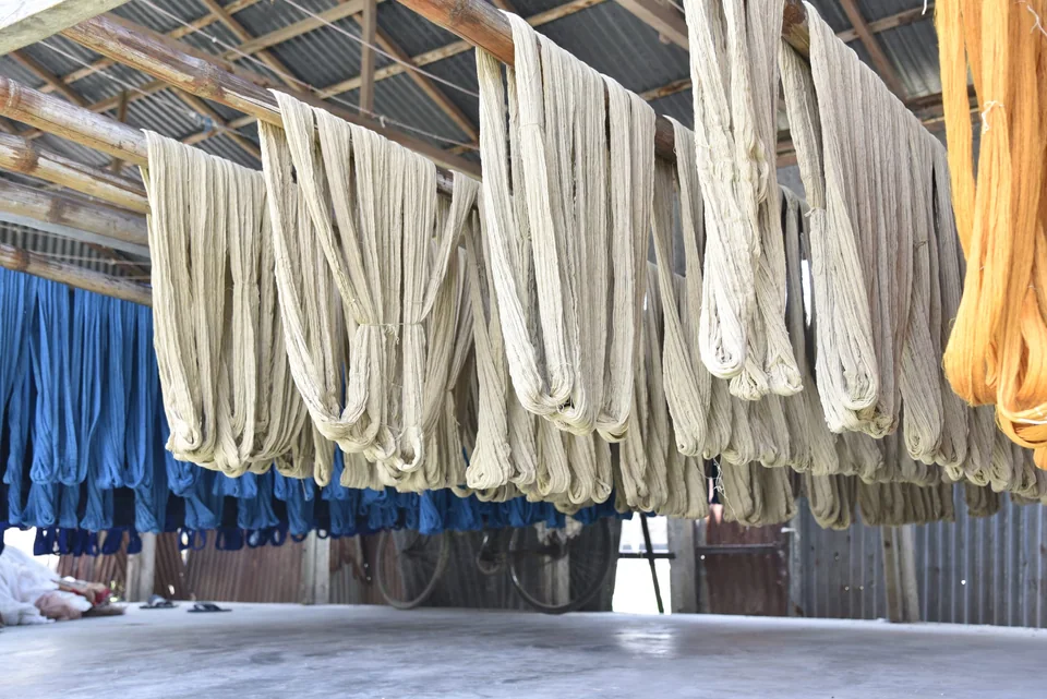 Rows of washed yarn hung to dry under a shed roof